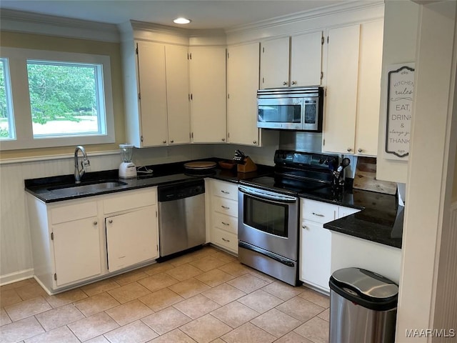 119 Mallory Dr, Selma, AL 36701 - kitchen featuring appliances with stainless steel finishes, dark countertops, ornamental molding, light tile patterned floors, and white cabinetry