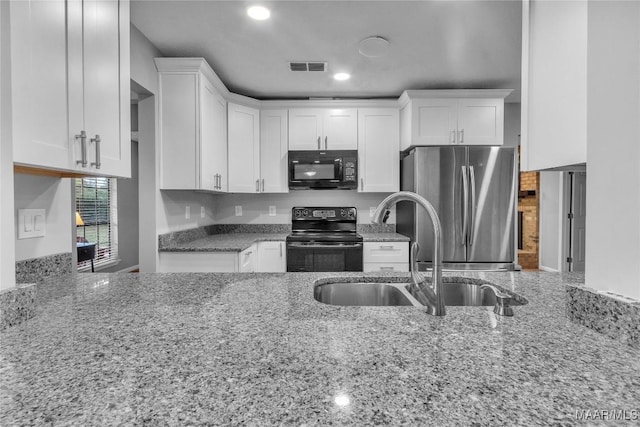 113 Duck Cv, Elmore, AL 36025 - kitchen featuring black appliances, light stone counters, white cabinets, recessed lighting, and a peninsula