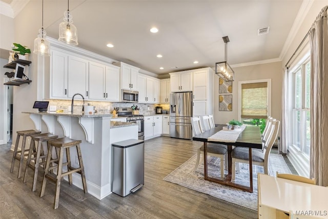 529 Hickory Dr, Wetumpka, AL 36092 - kitchen featuring appliances with stainless steel finishes, crown molding, a peninsula, white cabinetry, and dark wood-type flooring