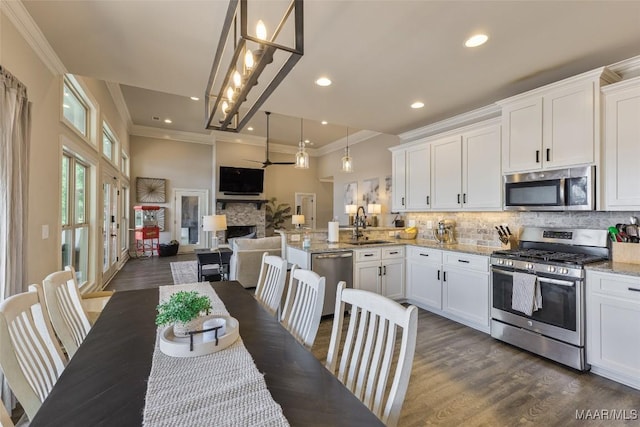 529 Hickory Dr, Wetumpka, AL 36092 - kitchen featuring appliances with stainless steel finishes, a peninsula, ornamental molding, white cabinetry, and decorative backsplash