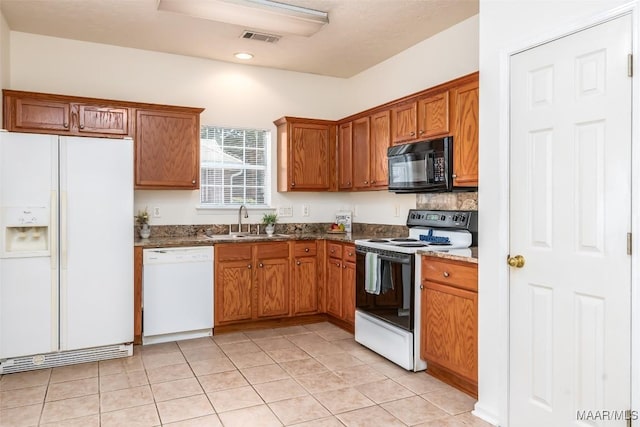 422 River Oaks Dr, Wetumpka, AL 36092 - kitchen featuring white appliances, brown cabinets, dark stone counters, light tile patterned floors, and recessed lighting