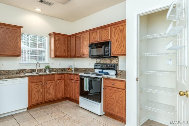 422 River Oaks Dr, Wetumpka, AL 36092 - kitchen with white appliances, brown cabinetry, light tile patterned flooring, dark stone countertops, and recessed lighting