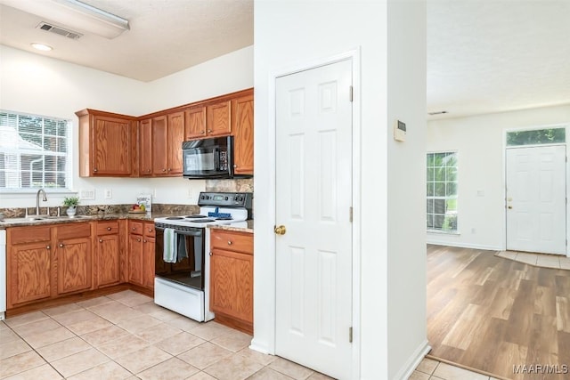 422 River Oaks Dr, Wetumpka, AL 36092 - kitchen with electric range, black microwave, brown cabinetry, light tile patterned floors, and dark stone countertops