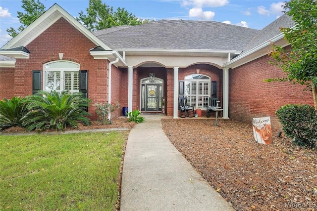 145 Mountain Meadows Ln, Wetumpka, AL 36093 - view of exterior entry with brick siding, roof with shingles, and a yard