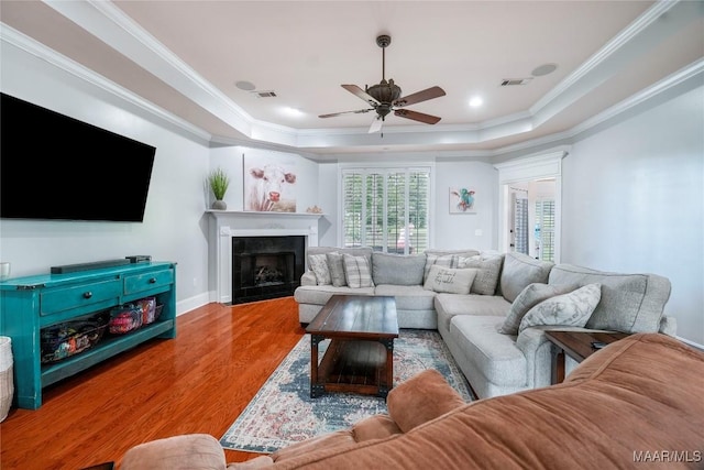 145 Mountain Meadows Ln, Wetumpka, AL 36093 - living area featuring a raised ceiling, wood finished floors, a fireplace with flush hearth, ceiling fan, and crown molding