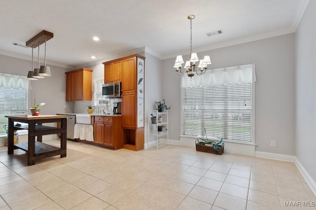 204 St Thomas Ave, Wetumpka, AL 36092 - kitchen featuring stainless steel microwave, plenty of natural light, light tile patterned flooring, crown molding, and brown cabinets