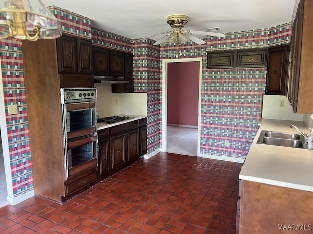 216 Cone Dr, Selma, AL 36701 - kitchen with stainless steel double oven, ceiling fan, light countertops, under cabinet range hood, and brick floors