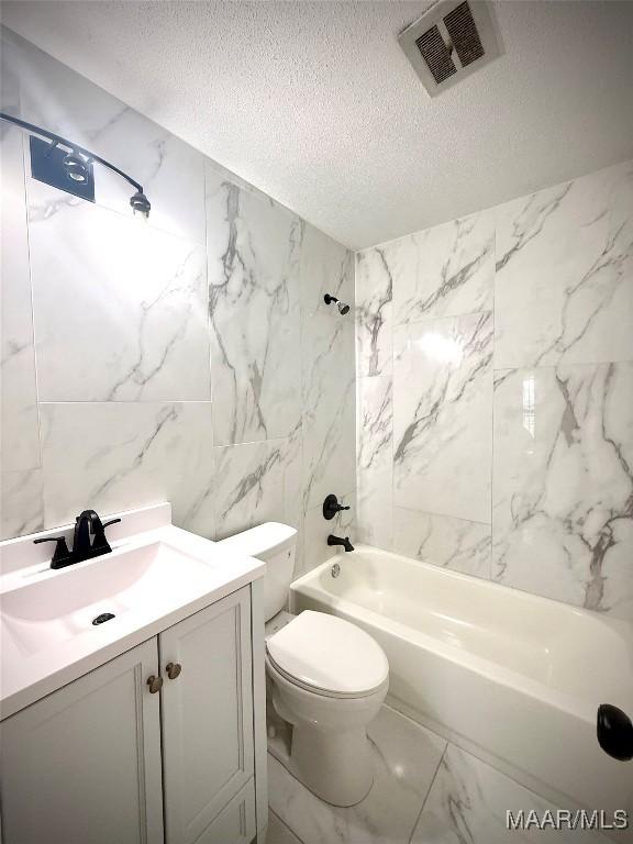 5204 Patricia Ln, Montgomery, AL 36108 - full bathroom featuring a textured ceiling, washtub / shower combination, vanity, marble finish floors, and tile walls