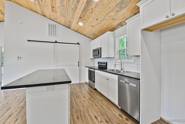 1415 Gold Mine Branch Rd, Marbury, AL 36051 - kitchen featuring stainless steel appliances, wooden ceiling, dark countertops, a barn door, and vaulted ceiling