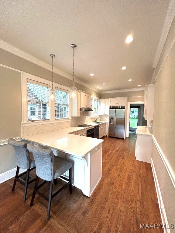 2412 College St, Montgomery, AL 36106 - kitchen with stainless steel fridge with ice dispenser, a peninsula, crown molding, dark wood-style floors, and under cabinet range hood