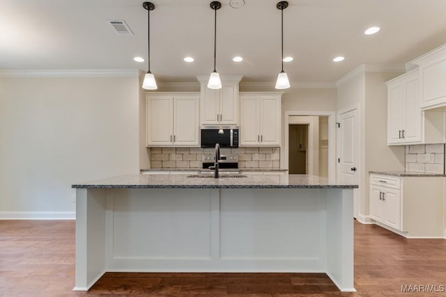79 Birchwood Ln, Wetumpka, AL 36093 - kitchen with stainless steel microwave, ornamental molding, stone countertops, decorative backsplash, and an island with sink