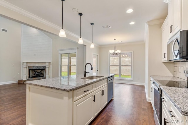 79 Birchwood Ln, Wetumpka, AL 36093 - kitchen featuring appliances with stainless steel finishes, dark wood finished floors, a fireplace with raised hearth, ornamental molding, and light stone counters