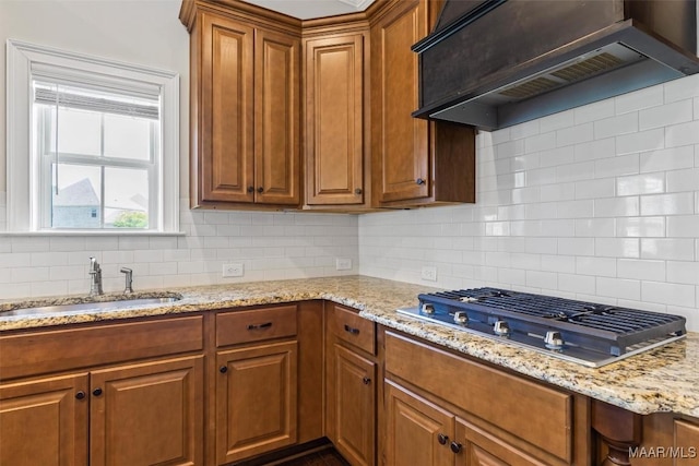 8465 Melbourne Cir, Montgomery, AL 36117 - kitchen featuring stainless steel gas cooktop, premium range hood, backsplash, brown cabinets, and light stone countertops