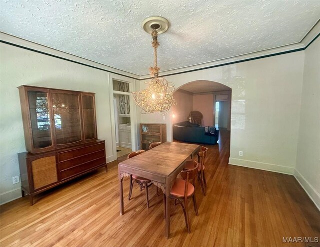 3319 Lexington Rd, Montgomery, AL 36106 - dining space with light wood-style floors, a textured ceiling, a chandelier, arched walkways, and ornamental molding