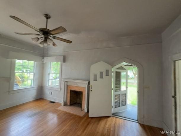 158 S Madison Ter, Montgomery, AL 36107 - unfurnished living room with wood finished floors, ceiling fan, a fireplace, and arched walkways