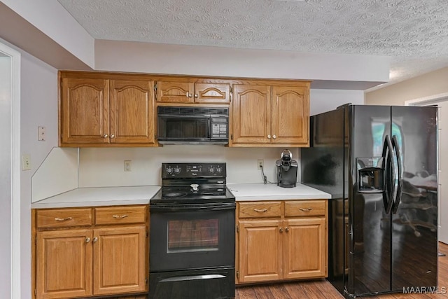 165 Ten Cedars Dr, Titus, AL 36080 - kitchen featuring black appliances, a textured ceiling, wood finished floors, light countertops, and brown cabinetry