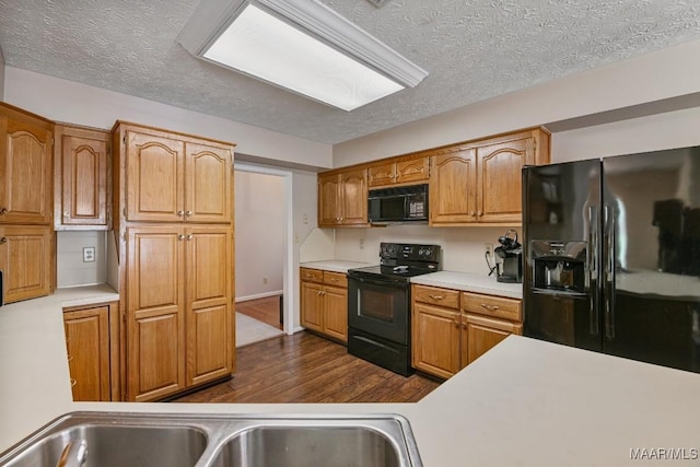 165 Ten Cedars Dr, Titus, AL 36080 - kitchen featuring black appliances, dark wood-style flooring, a textured ceiling, light countertops, and brown cabinetry