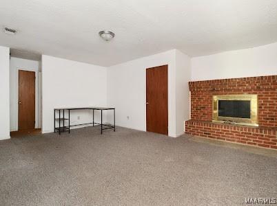 1219 First Ave, Tuskegee, AL 36088 - unfurnished living room with carpet and a fireplace
