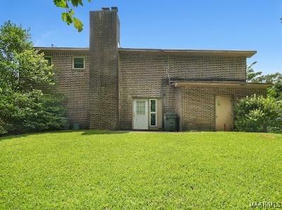 1219 First Ave, Tuskegee, AL 36088 - rear view of house with a lawn, a chimney, and brick siding