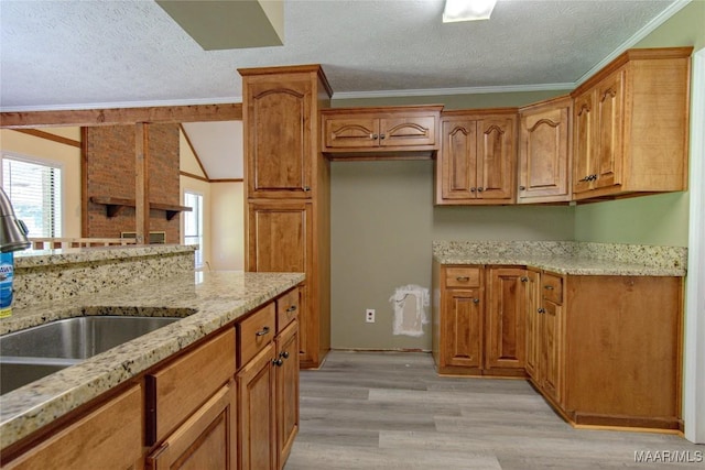 1245 Providence Rd, Titus, AL 36080 - kitchen with a textured ceiling, light stone countertops, light wood-style flooring, ornamental molding, and brown cabinets