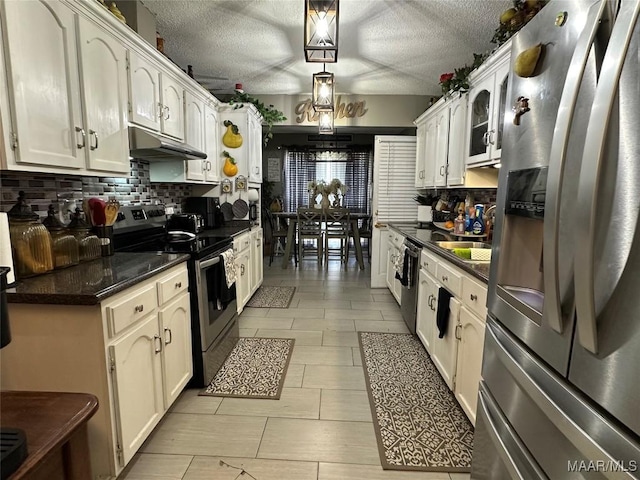4525 Lisa Ct, Montgomery, AL 36106 - kitchen with appliances with stainless steel finishes, under cabinet range hood, dark countertops, backsplash, and white cabinetry