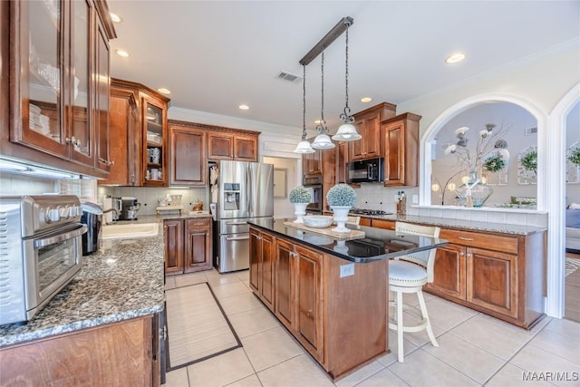 742 Mckeithen Pl, Millbrook, AL 36054 - kitchen with appliances with stainless steel finishes, decorative backsplash, light tile patterned floors, a kitchen island, and brown cabinetry