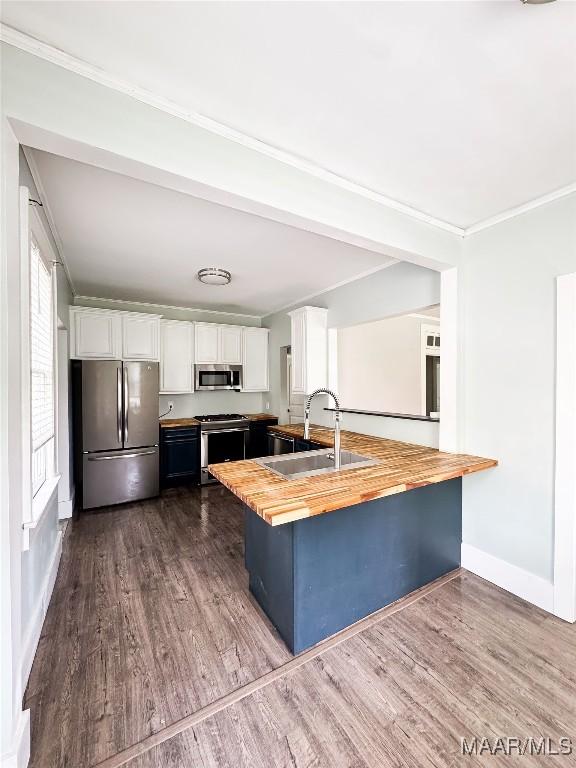 3155 Wilmington Rd, Montgomery, AL 36105 - kitchen featuring stainless steel appliances, wood counters, white cabinets, dark wood finished floors, and crown molding