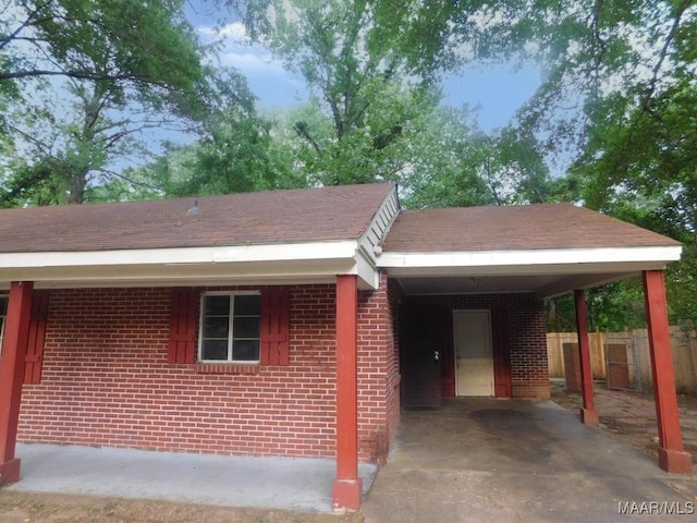 3659 Cloverdale Rd, Montgomery, AL 36111 - view of front facade featuring an attached carport, brick siding, a shingled roof, and driveway