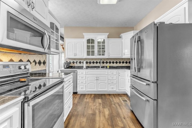 215 Hickory Rd, Titus, AL 36080 - kitchen featuring appliances with stainless steel finishes, white cabinets, dark wood finished floors, tasteful backsplash, and a textured ceiling