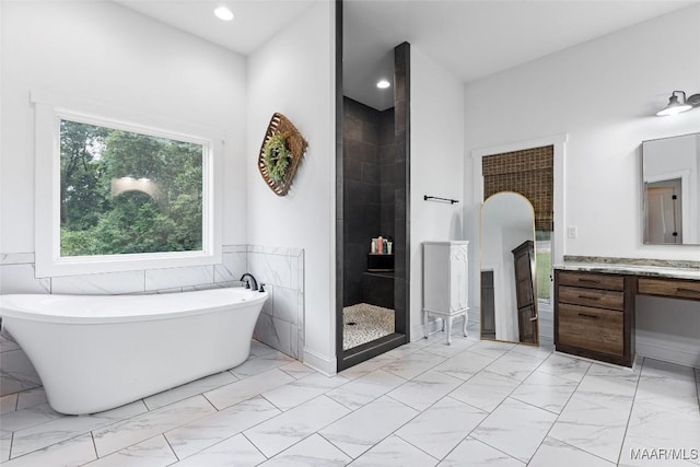 362 Driver Rd, Deatsville, AL 36022 - bathroom featuring marble look tile flooring, a freestanding bath, vanity, tiled shower, and a wainscoted wall
