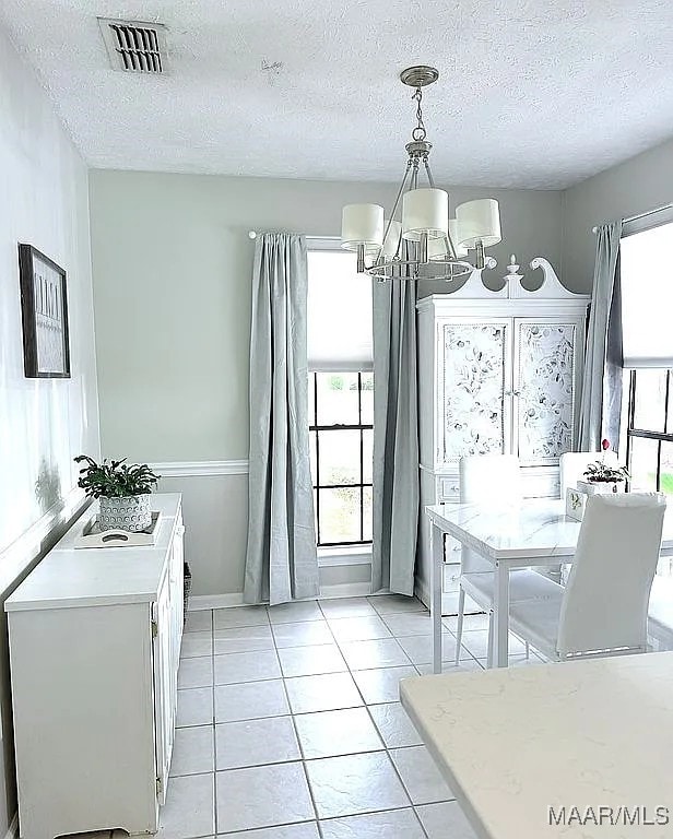 312 Rebekah Ln, Montgomery, AL 36109 - dining area with a chandelier, a textured ceiling, healthy amount of natural light, and light tile patterned flooring
