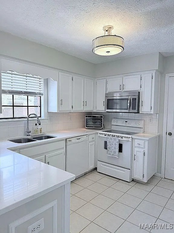 312 Rebekah Ln, Montgomery, AL 36109 - kitchen featuring white appliances, light countertops, a textured ceiling, and white cabinets