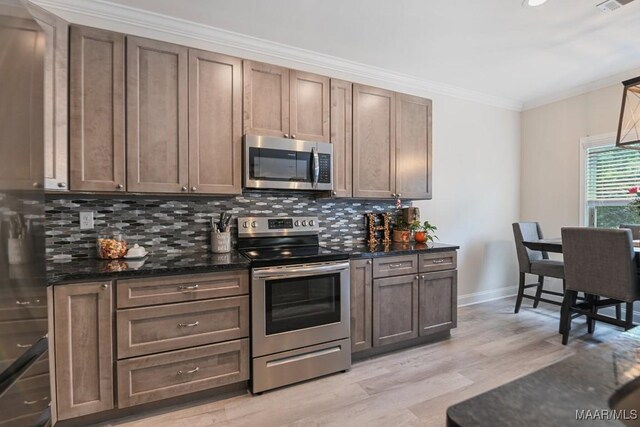 174 Shadow Wood Ln, Wetumpka, AL 36092 - kitchen featuring stainless steel appliances, ornamental molding, light wood-style flooring, tasteful backsplash, and dark stone counters