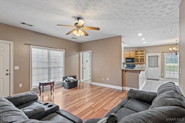 1018 Austin St, Wetumpka, AL 36092 - living room with light wood-style floors, a ceiling fan, a chandelier, recessed lighting, and a textured ceiling