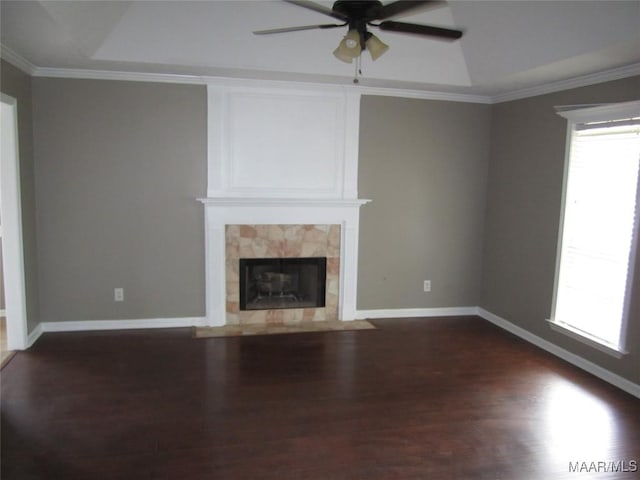unfurnished living room with a ceiling fan, healthy amount of natural light, dark wood-style floors, a tile fireplace, and ornamental molding