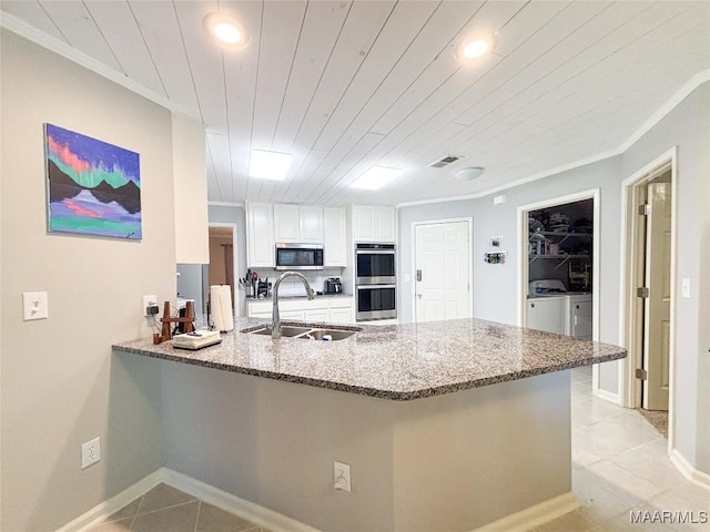 7908 Arrowhead Forest Ct, Montgomery, AL 36117 - kitchen featuring stainless steel appliances, washing machine and clothes dryer, a peninsula, light tile patterned flooring, and stone countertops