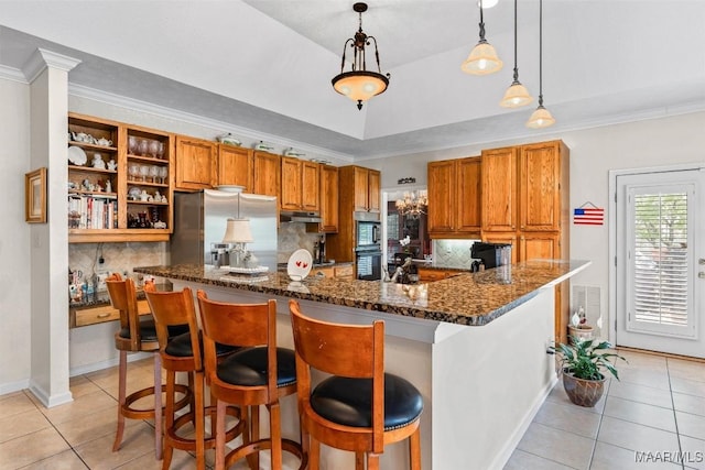 8872 Old Magnolia Way, Montgomery, AL 36116 - kitchen featuring appliances with stainless steel finishes, light tile patterned floors, under cabinet range hood, brown cabinets, and dark stone counters