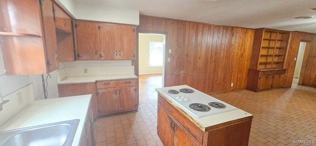 2804 Sumter Ave, Montgomery, AL 36109 - kitchen featuring wooden walls, white electric cooktop, light countertops, brown cabinetry, and brick patterned flooring
