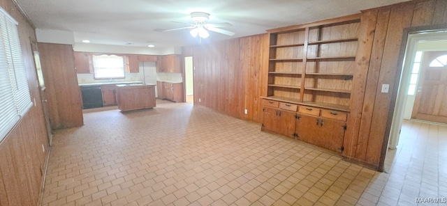 2804 Sumter Ave, Montgomery, AL 36109 - kitchen featuring a ceiling fan, wood walls, brown cabinets, light countertops, and a kitchen island