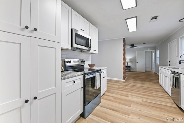 506 Lilly Ave, Tallassee, AL 36078 - kitchen with appliances with stainless steel finishes, tasteful backsplash, white cabinetry, light wood-style flooring, and ornamental molding