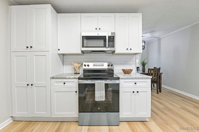 506 Lilly Ave, Tallassee, AL 36078 - kitchen with stainless steel appliances, backsplash, light wood-style flooring, and white cabinets