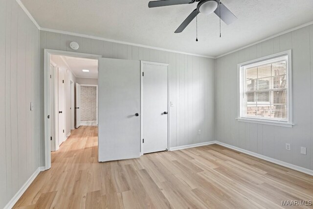 506 Lilly Ave, Tallassee, AL 36078 - unfurnished bedroom featuring ornamental molding, light wood-style flooring, a ceiling fan, and wood walls