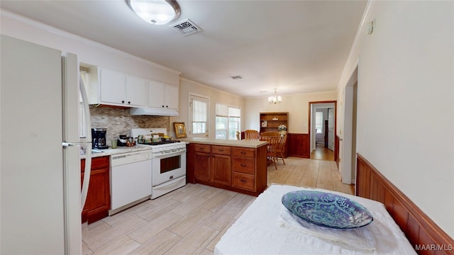 1706 Celia Ct, Montgomery, AL 36106 - kitchen with white appliances, a peninsula, a chandelier, under cabinet range hood, and a wainscoted wall