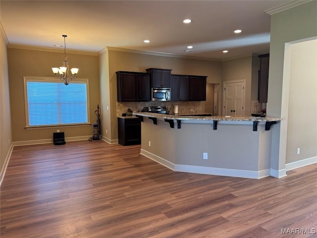 3701 Weston Pl, Montgomery, AL 36116 - kitchen featuring appliances with stainless steel finishes, a breakfast bar, wood finished floors, a chandelier, and crown molding