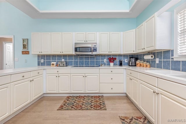 285 Cedar Ridge Dr, Wetumpka, AL 36093 - kitchen with stainless steel microwave, light countertops, tasteful backsplash, white cabinets, and black electric cooktop
