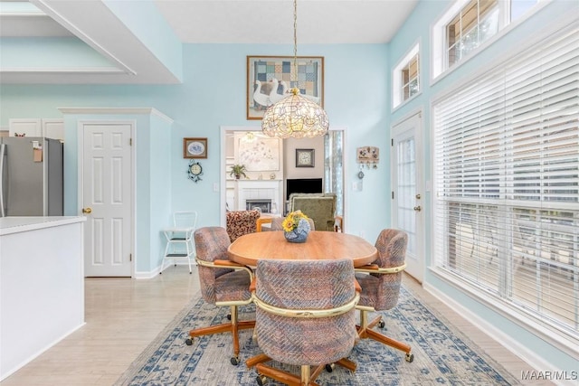 285 Cedar Ridge Dr, Wetumpka, AL 36093 - dining area with a chandelier, light wood finished floors, a fireplace, and a towering ceiling