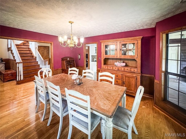 1267 County Road 85th Rd, Prattville, AL 36067 - dining area featuring a textured ceiling, a chandelier, a wainscoted wall, light wood finished floors, and stairs