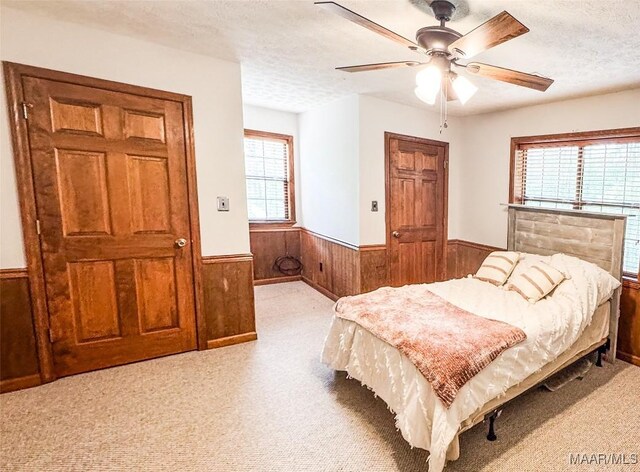 1267 County Road 85th Rd, Prattville, AL 36067 - bedroom with wainscoting, wooden walls, multiple windows, a textured ceiling, and light colored carpet