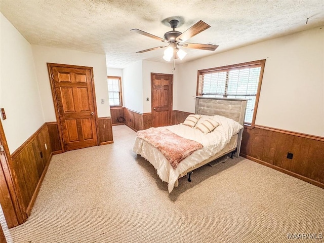 1267 County Road 85th Rd, Prattville, AL 36067 - carpeted bedroom with a wainscoted wall, wood walls, multiple windows, a textured ceiling, and a ceiling fan