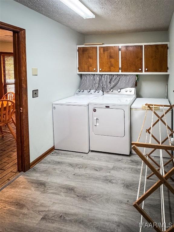 1267 County Road 85th Rd, Prattville, AL 36067 - washroom with cabinet space, separate washer and dryer, light wood-style flooring, and a textured ceiling